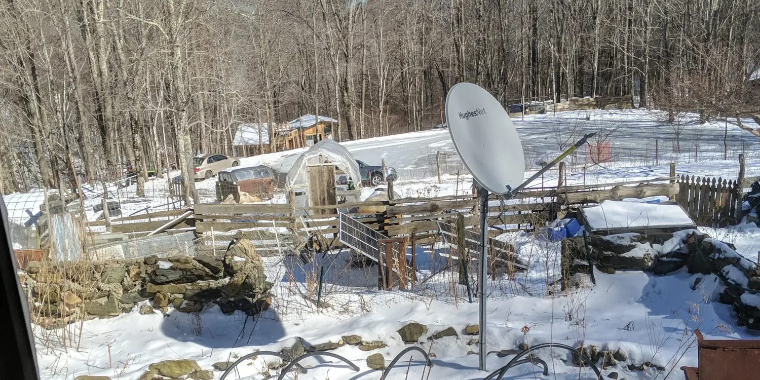 An image of a farm. Solar panels in the middle, a satellite dish in the foreground.