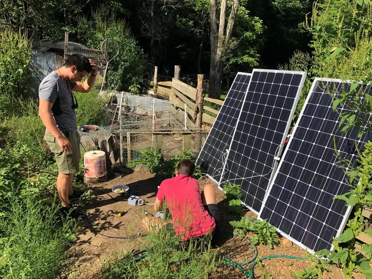 Three solar panels leaning against a fence